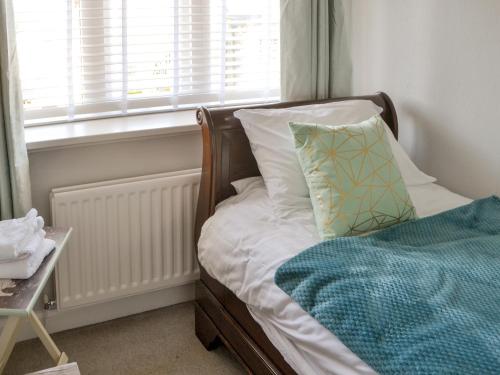 a bedroom with a bed with a pillow and a window at Littlecroft in Alnmouth