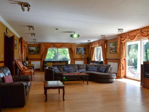 ein Wohnzimmer mit Sofas und Stühlen und Fenstern in der Unterkunft Vijay Gardens in Glanamman