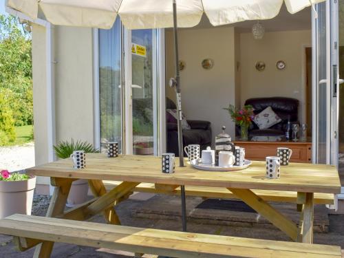 a wooden table with mugs and an umbrella at Green Valley Retreat in Holsworthy