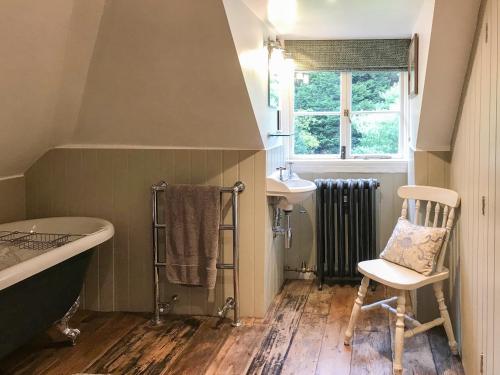 FernhurstにあるOld Rectory Loftのバスルーム(バスタブ、シンク、椅子付)