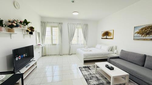 a living room with a couch and a tv at Z01 Furnished Studio Garden view International city in Dubai