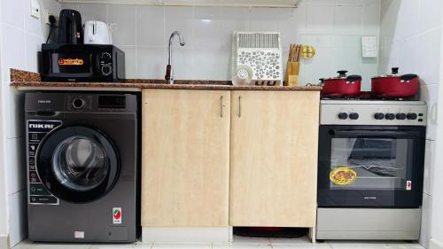 a kitchen with a washing machine and a stove at Z01 Furnished Studio Garden view International city in Dubai
