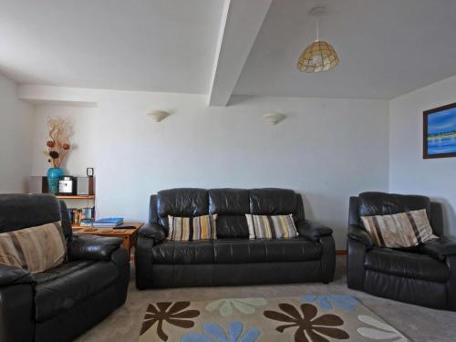 a living room with two black leather couches and a rug at The Old Chandlery in Avoch