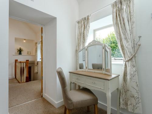 a dressing table with a mirror and a chair at Waterside Barn in Bradbourne