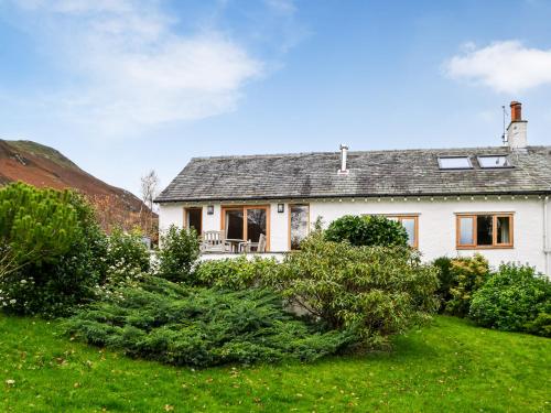 a white house with a yard with bushes at Over Brandelhow in Borrowdale Valley