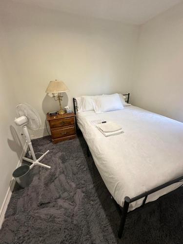 a bedroom with a bed and a table with a lamp at Goldwin's Place in Toronto