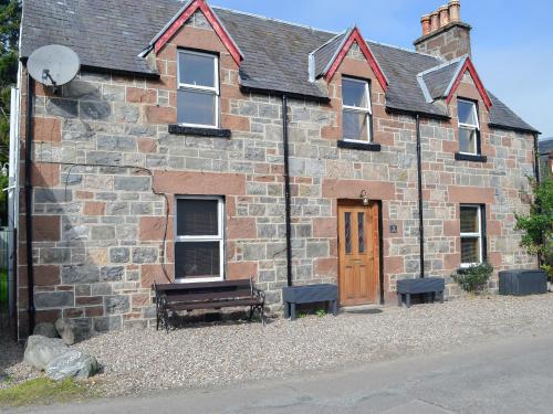 an old brick building with a wooden door and a bench at East Lewiston in Drumnadrochit