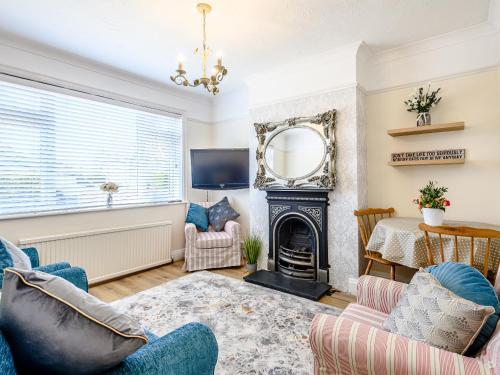 a living room with a fireplace and a mirror at Grayson Avenues in Pakefield