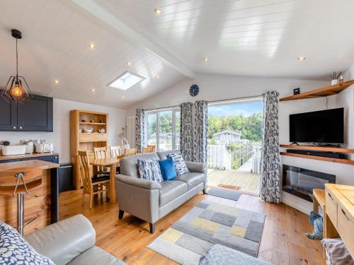 a living room with a couch and a kitchen with a table at Lilac Tree Lodge in Willington