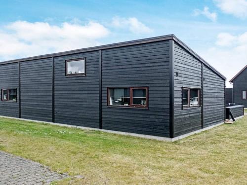 a black house with windows on a grass field at Exclusive Retreat with Spa - By Traum Ferienwohnungen in Rømø Kirkeby