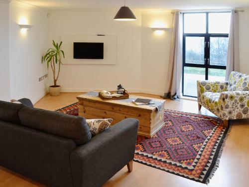 Una sala de estar con un sofá y una mesa de café. en Linhay Apartment, en St Austell