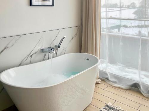 a white bath tub in a bathroom with a window at The Bungalow in Rushton Spencer