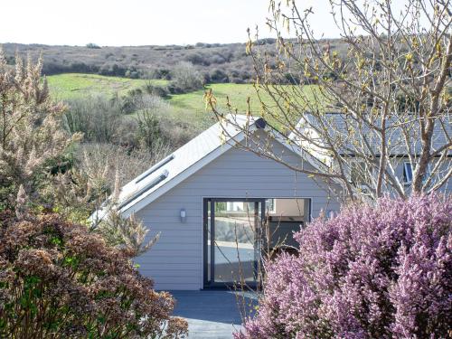 a small white house with a window and some bushes at Little Foxes in Perranporth