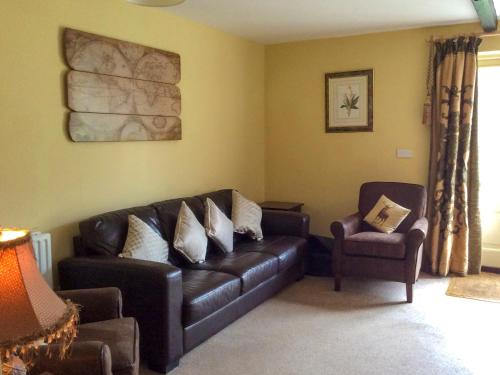 ein Wohnzimmer mit einem Ledersofa und einem Stuhl in der Unterkunft Carrot Cottage - Uk32609 in Manton