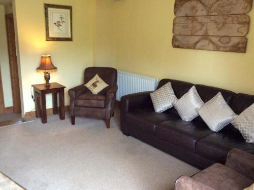 ein Wohnzimmer mit einem Ledersofa und einem Stuhl in der Unterkunft Carrot Cottage - Uk32609 in Manton