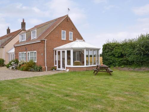 a brick house with a whiteconservatory in the yard at Iris Apartment in Stalham