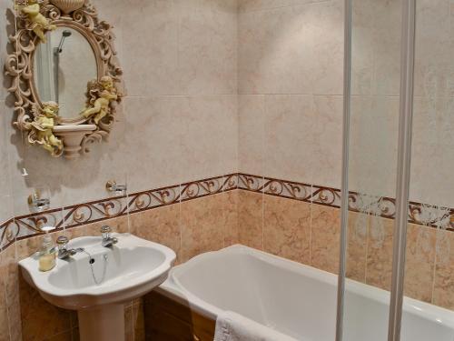 a bathroom with a sink and a tub and a mirror at Pheasant Roost in Swanton Morley