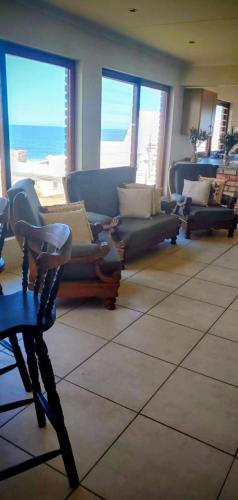 a living room with couches and a table and windows at C - Views in Jongensfontein