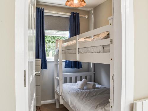a bedroom with bunk beds in a room with blue curtains at Seals Cove in Polzeath