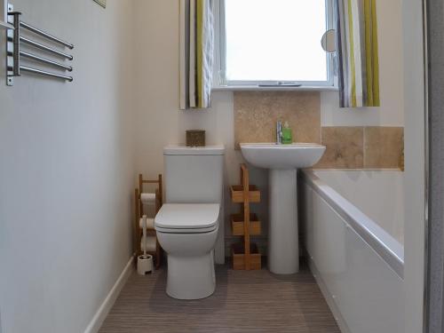 a bathroom with a toilet and a sink and a window at Sea La Vie in Mundesley