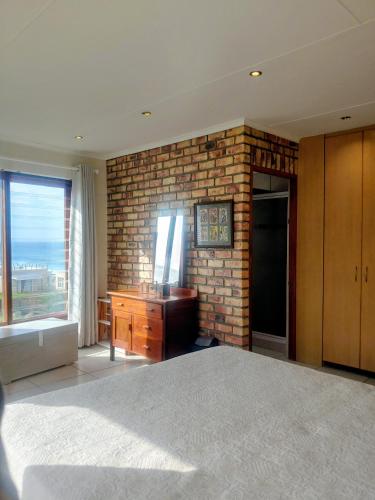 a bedroom with a brick wall with a bed and a dresser at C - Views in Jongensfontein