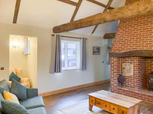 a living room with a brick fireplace and a couch at The Dairy - Uk48866 in Aylsham