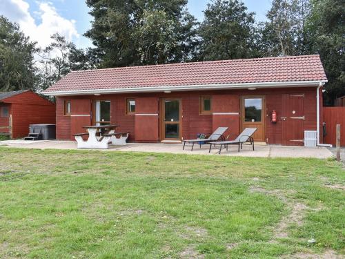 a red building with two benches in front of it at Sherwood Forest Lodge 2 in Clipstone