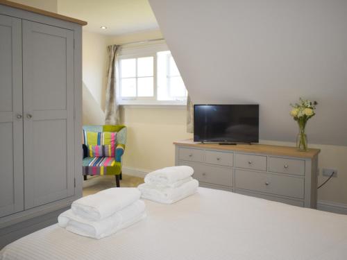 a bedroom with a bed with a television and a chair at Puxton Lodge in Fordwich