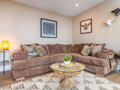 a living room with a brown couch and a table at Hayloft - Uk49529 in Buchlyvie