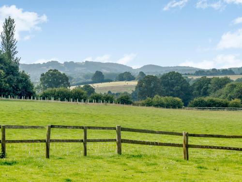 a wooden fence in a green field with trees at The Bothy in Mathon