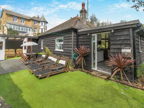 een huis met een tuin met stoelen en een patio bij By The Beach- Uk31201 in Downderry