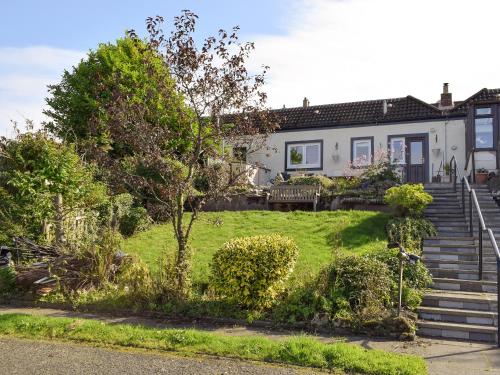 een huis met een trap en een grasveld bij Dothan Farm Cottage in Cardenden