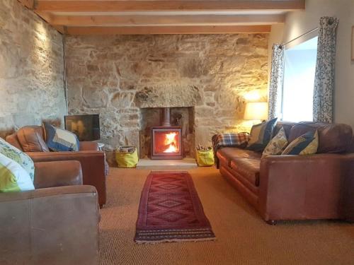 un soggiorno con mobili in pelle e camino in pietra di Stone Cottage a Elgol