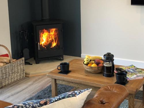 a living room with a fireplace and a table with a bowl of fruit at The Old Dairy - Uk31253 in Middleton