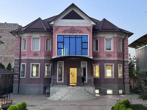 una casa rosa con puerta amarilla en Мечта 27, en Bishkek