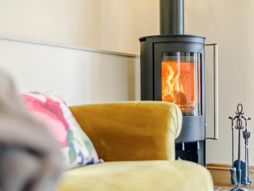 a living room with a fireplace and a yellow couch at Alton Hall Cottage in Ashover