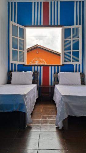 due letti in una stanza con finestra di Hospedagem Aldeia Multiétnica a Alto Paraíso de Goiás
