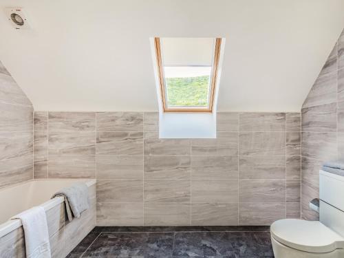 a bathroom with a tub and a window at Headland View in Banff