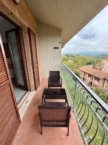 two chairs and tables on a balcony with a view at Appartamento Panoramico Urbino Vista Colline in Urbino