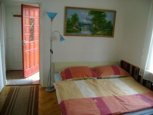 a bedroom with a bed and a lamp and a door at Sóstó Apartman in Siófok