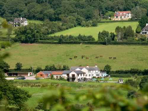 a group of houses in a field with horses in the distance at The Hay Barn in Sidbury