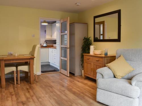 a living room with a couch and a table and a kitchen at Old Orchard Cottage Near Eden in Luxulyan