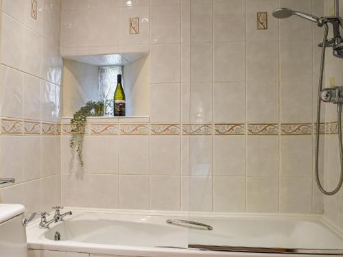 a bathroom with a tub and a bottle of wine at The Stables in Waltham on the Wolds