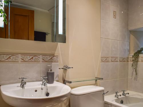a bathroom with a sink and a toilet and a mirror at The Stables in Waltham on the Wolds