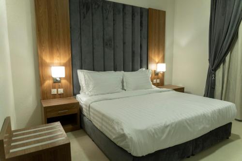 a bedroom with a large bed and two night stands at واحة الضيافة للشقق الفندقية Wahat Aldiyafah Hotel Apartments in Buraydah