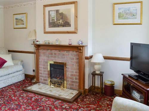 a living room with a fireplace and a tv at Cow Pasture Cottage - Uk2297 in Ebberston