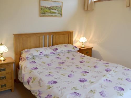 a bedroom with a bed with a purple comforter at Orchard View Barn in Plymtree