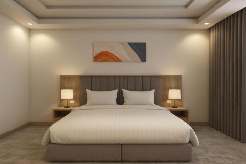 a bedroom with a large white bed with two lamps at أجنحة هدوء وصول ذاتي in Medina