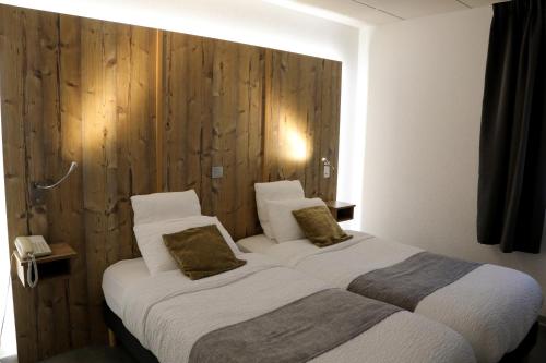 two beds in a hotel room with wooden walls at Logis Hotel des Cépages in Arbois