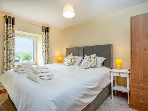 a bedroom with a large white bed with a window at Trelawney Cottage in Charlestown